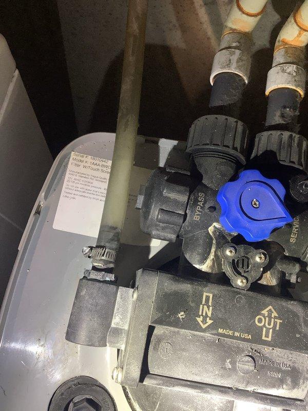 Responded to water treatment system leak originating from the rear of the acid neutralizer. Upon arrival, found leak at bypass valve assembly and successfully placed system in bypass mode to control water loss. Performed comprehensive inspection of entire water treatment system including acid neutralizer and associated components. Evaluated system for potential re-bed requirements and salt levels, noting last re-bed was completed with neutralizing solution mix in April 2024. Documented current system condition with photographs showing bypass valve configuration, piping connections, and treatment tank assembly for service records.