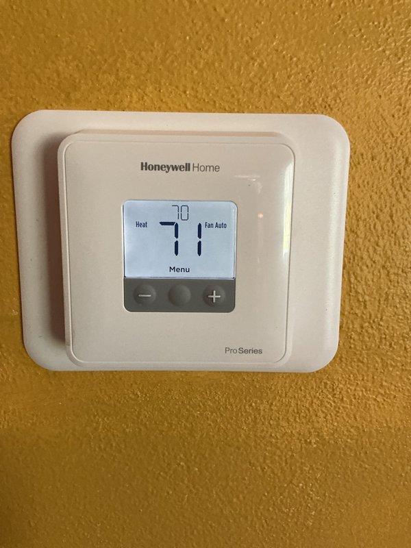Responded to service call for oil heating system not operating after homeowner replaced thermostat batteries. Upon arrival, found Honeywell Home Pro Series digital thermostat displaying numbers but system failing to call for heat. Verified thermostat was receiving power and display was functioning properly at 71 degrees in heat mode with fan set to auto. Inspected basement mechanical room and examined oil-fired heating system, humidifier unit, and associated ductwork connections. Diagnosed thermostat programming issue following battery replacement which reset system settings. Reprogrammed thermostat to correct parameters and verified proper communication between thermostat and heating system. Cycled system through complete heating cycle to confirm proper operation and heat delivery throughout home.