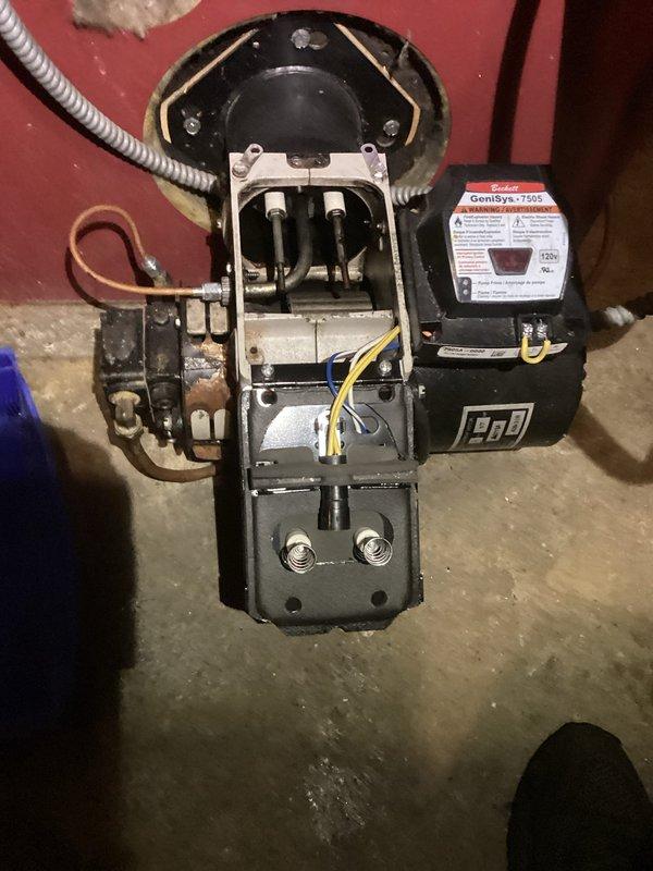Performed annual cleaning and service on the oil-fired heating system, including removal and cleaning of the burner nozzle and ignition electrode assembly on the Beckett GenSys 7505 burner. Inspected the burner housing, motor, control, and fuel pump assembly, noting corrosion on the fuel pump, and restored the system to proper operation to address the customer's reported lack of heat at the 72-degree thermostat setting.