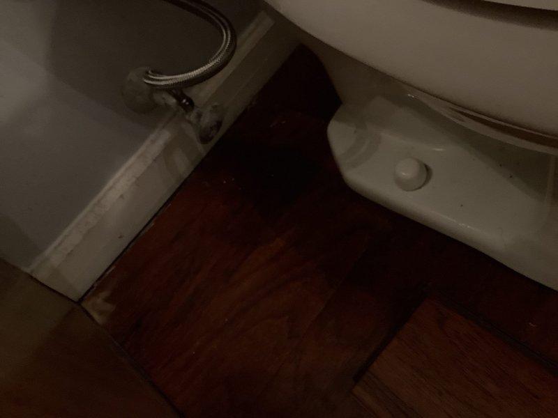 Shut off the water supply at the angle stop, drained the tank, disconnected the braided supply line, and removed the toilet to allow floor work in the bathroom. Upon removal, moisture staining was observed on the hardwood subfloor near the toilet base and wall. After the flooring work was completed, the toilet was reset on the floor, secured with closet bolts, reconnected to the supply line, and the water supply was restored and tested for proper operation and leaks.