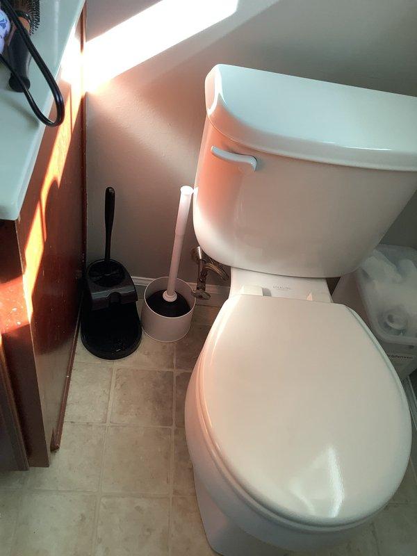 Inspected the upstairs toilet for a leak at the base and examined the tank internals, finding a heavily corroded float arm and fill valve with mineral buildup and sediment throughout the tank. Evaluated the supply line and shutoff valve connection and the base seal as potential leak sources, and documented the aged, rusted components as contributing to the water issue.