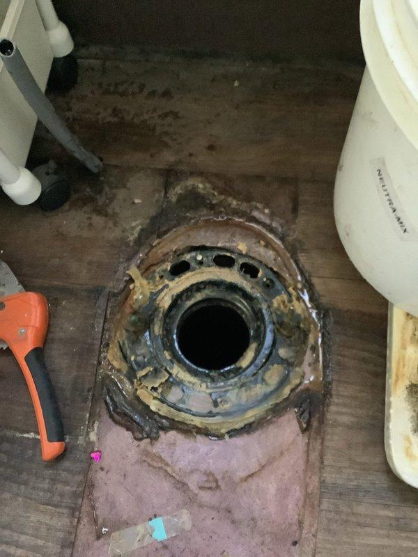 Inspected loose toilets and removed one fixture, exposing a corroded closet flange with old wax ring residue set into a rotted, water-damaged subfloor. Because the damaged flooring cannot support a proper reset, the toilet was left disconnected pending subfloor repair, and the drain opening was secured. The drain stop retrieval and UV bulb replacement were not completed during this visit.