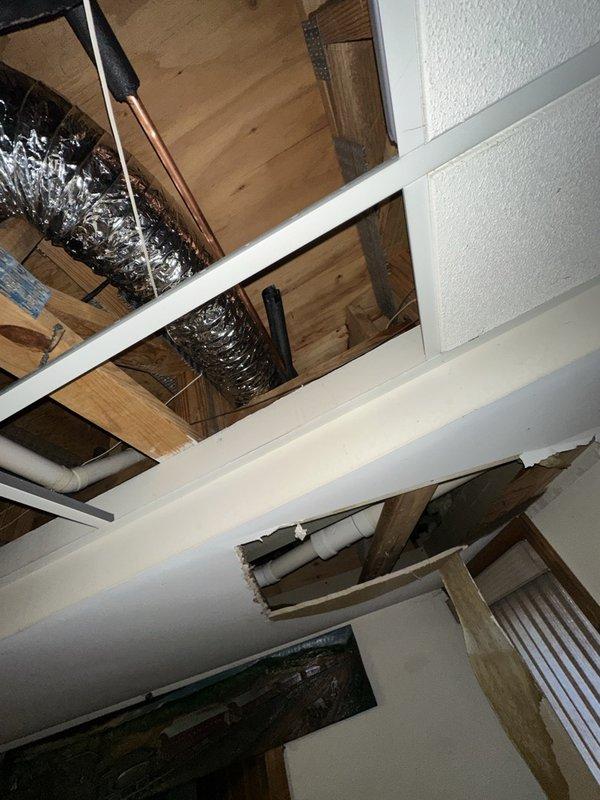Responded to a burst pipe in the bathroom that had released water into the surrounding living space and required the main water supply to be shut off. Inspected the ceiling cavity and floor assembly below, locating the failed supply line and the resulting water damage, including a torn drywall section and moisture staining on the subfloor and joists. Isolated and repaired the leaking pipe, then restored water service and checked the system for leaks.