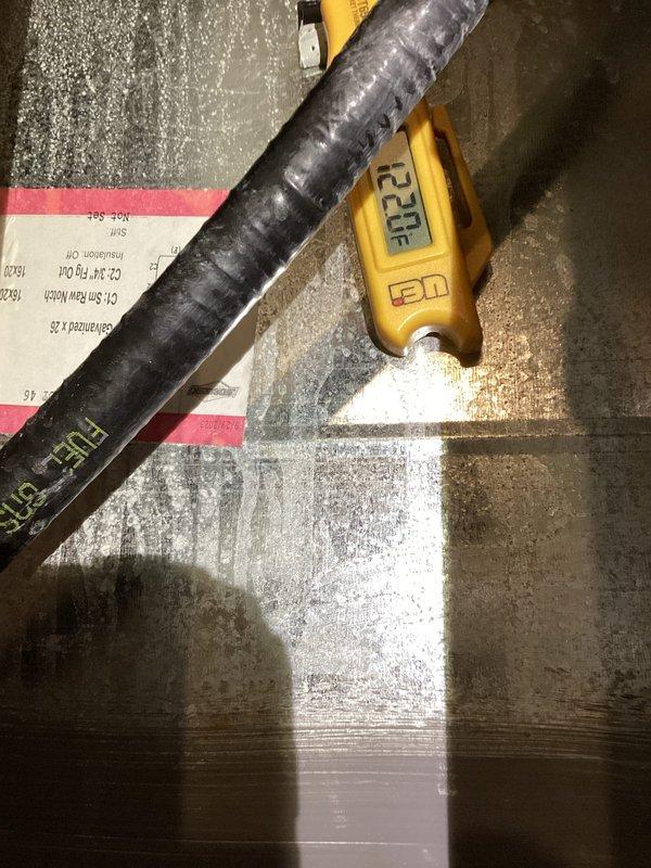 Performed a gas furnace tune-up and inspection in response to a reported water leak, finding water pooled around the base of the natural gas unit. Inspected the interior components, including the inducer blower housing and plastic collector box, where a hairline crack and sealant was noted near the condensate pipe fitting as a likely source of the leak. Verified operation with a digital thermometer probe on the ductwork (122°F reading) and completed the gas heating system check.