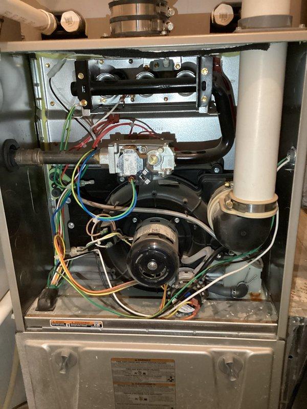 Performed a complete gas furnace tune-up on an existing Carrier unit, including removal of the front access panel and inspection of the burner assembly, gas valve and piping, inducer/draft blower, blower motor, wiring harness, and PVC venting and drain connections. Verified thermostat operation, and found the system operating normally with no deficiencies. Noted light dust accumulation and minor rust-colored staining near the blower drain fitting, which should be monitored at future maintenance visits.