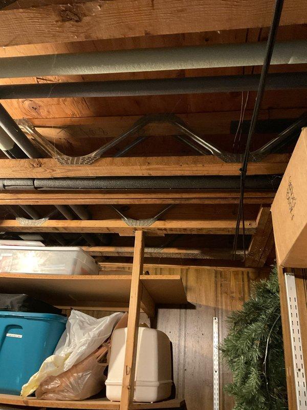Conducted site assessment of residential property with existing boiler heating system to provide replacement options for AC installation. Inspected unfinished basement area with exposed joists and utility runs to evaluate potential installation pathways. Documented current thermostat location in hallway for integration with new AC system.