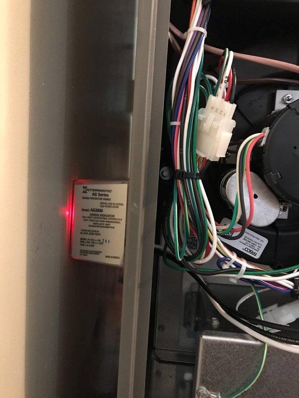 Responded to callback for surge protector showing red indicator light following recent power outage. Inspected Intermatic surge protection device in electrical panel and confirmed alarm status. Reset protection system and verified proper operation with green indicator light now showing normal function.