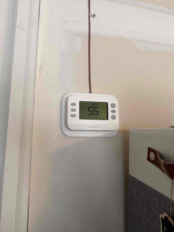 Responded to callback to address venting issues from previous installation. Rotated exterior vent tee to vertical position and extended it away from wall per permit requirements. Applied fire caulk to seal all venting joints for proper code compliance. Verified thermostat functioning correctly at 55°F in heating mode.