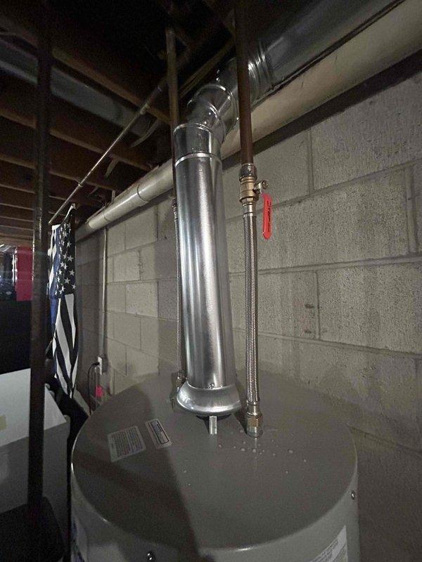 Successfully installed new tanked water heater in basement utility area, including proper connection of all supply lines and drain piping. Installed metal exhaust vent pipe with appropriate 90-degree bend, securing it properly to the concrete block wall. Verified all connections for leaks and confirmed proper operation before completion.
