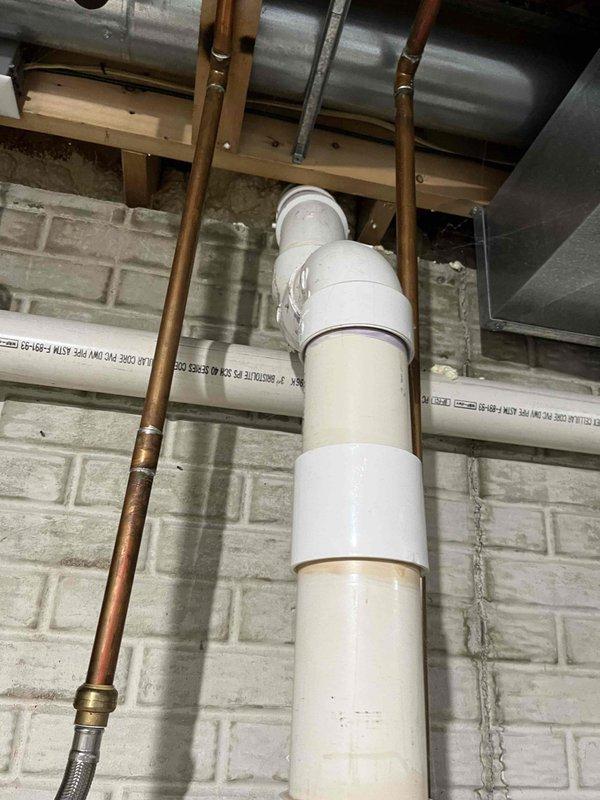 Responded to complaint of water heater running out of hot water mid-shower. Inspected tanked water heater installation including supply lines, venting system, and electrical connections in mechanical space. Evaluated copper supply piping, PVC vent piping, and associated mounting hardware for proper installation and function. Documented existing plumbing configuration including water supply connections, drain lines, and HVAC ductwork proximity to water heater system.