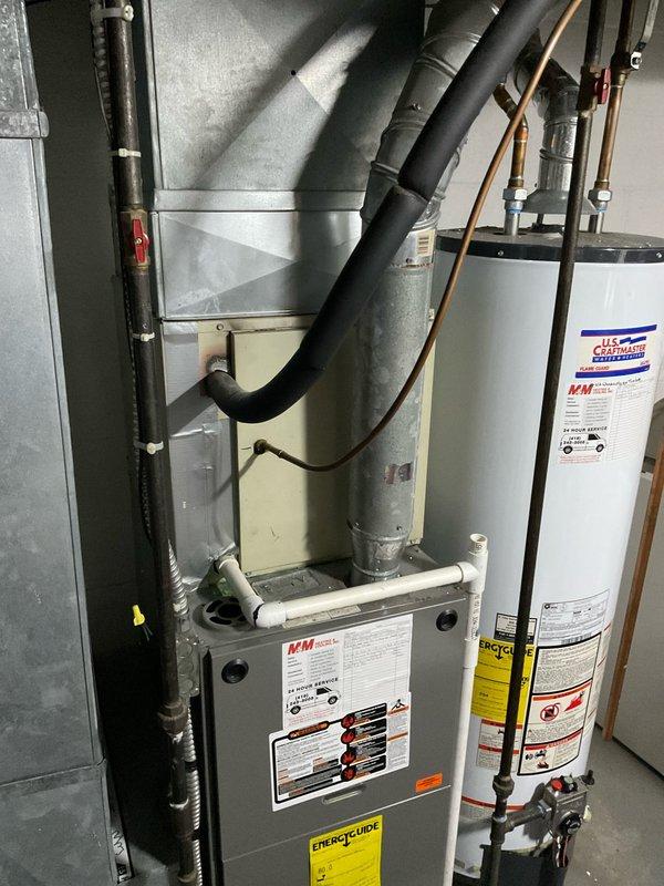 Conducted comprehensive site assessment of existing HVAC system located in basement utility room to provide equipment replacement estimate. Evaluated current gray metal furnace unit with associated ductwork and documented equipment specifications, age, operational status, and fuel type for replacement recommendations. Photographed existing installation configuration including furnace positioning, duct routing, clearances, and surrounding utilities including water heater and electrical systems to ensure accurate equipment sizing and proper replacement planning.