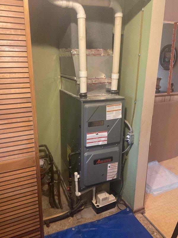 Performed comprehensive HVAC system evaluation for air conditioning replacement estimate. Customer reported no power to outdoor condensing unit. Upon inspection, confirmed aging R-22 refrigerant system requiring replacement due to obsolete refrigerant type and component failure. Outdoor unit exhibited no electrical power at disconnect. Indoor evaporator coil found severely contaminated with debris and biological growth, significantly restricting airflow and heat transfer efficiency. Tested dual capacitor on existing system and confirmed readings out of manufacturer specifications, indicating electrical component failure.

Documented existing Amana furnace installation in utility area with proper venting configuration via white PVC intake and exhaust piping. Photographed outdoor condensing unit positioned on concrete pad with existing electrical service and refrigerant line penetrations through exterior wall. Assessed installation location, clearances, and existing infrastructure for re