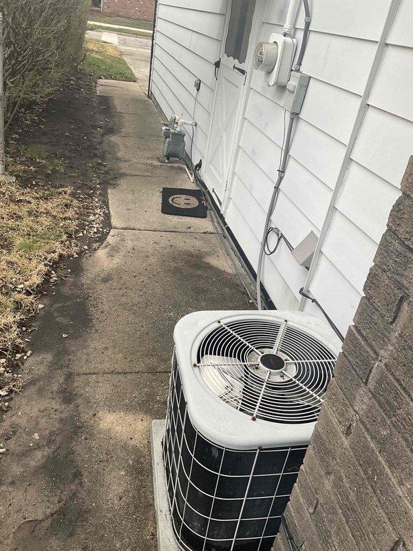 Performed comprehensive HVAC system evaluation for air conditioning replacement estimate. Customer reported no power to outdoor condensing unit. Upon inspection, confirmed aging R-22 refrigerant system requiring replacement due to obsolete refrigerant type and component failure. Outdoor unit exhibited no electrical power at disconnect. Indoor evaporator coil found severely contaminated with debris and biological growth, significantly restricting airflow and heat transfer efficiency. Tested dual capacitor on existing system and confirmed readings out of manufacturer specifications, indicating electrical component failure.

Documented existing Amana furnace installation in utility area with proper venting configuration via white PVC intake and exhaust piping. Photographed outdoor condensing unit positioned on concrete pad with existing electrical service and refrigerant line penetrations through exterior wall. Assessed installation location, clearances, and existing infrastructure for re