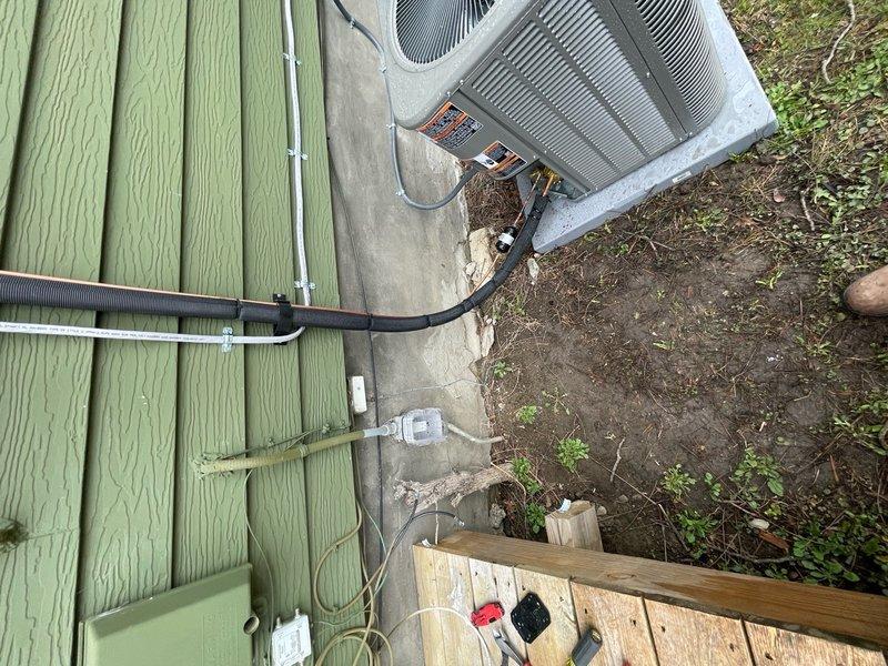 Installed new high voltage electrical line to support outdoor HVAC condenser unit. Ran black electrical conduit along exterior wall connecting to utility meter, ensuring proper power supply for air conditioning system operation.