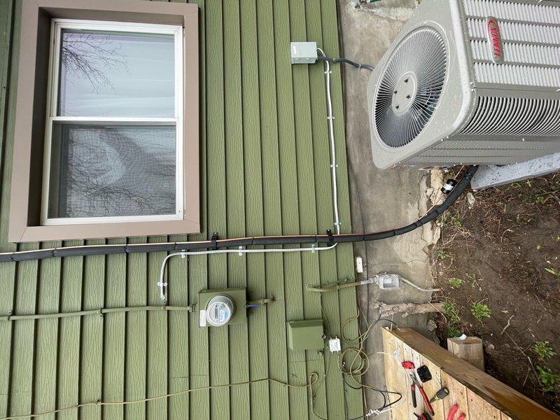 Installed new high voltage electrical line to support outdoor HVAC condenser unit. Ran black electrical conduit along exterior wall connecting to utility meter, ensuring proper power supply for air conditioning system operation.