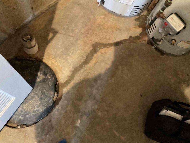 Conducted comprehensive assessment of basement utility area for water heater replacement estimate. Evaluated existing dual water heater installation, including Bradford White units with associated copper piping, ventilation ductwork, and support infrastructure. Documented significant water damage on concrete floor with extensive discoloration patterns indicating previous moisture intrusion or flooding events. Photographed current equipment configuration, mechanical connections, and surrounding HVAC components to develop accurate scope of work for proposed water heater replacement project.