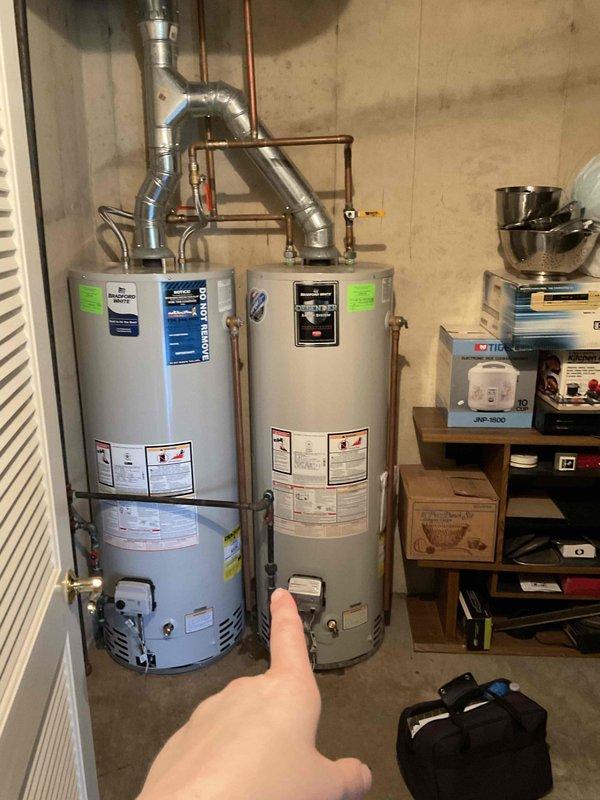 Conducted comprehensive assessment of basement utility area for water heater replacement estimate. Evaluated existing dual water heater installation, including Bradford White units with associated copper piping, ventilation ductwork, and support infrastructure. Documented significant water damage on concrete floor with extensive discoloration patterns indicating previous moisture intrusion or flooding events. Photographed current equipment configuration, mechanical connections, and surrounding HVAC components to develop accurate scope of work for proposed water heater replacement project.