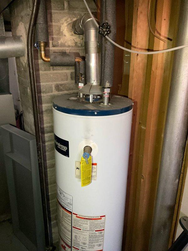 Conducted on-site evaluation and provided comprehensive quote for water heater replacement in residential basement utility area. Assessed existing white tank-style water heater installation, including venting configuration with metallic flue pipe, copper supply line connections, and insulated piping. Documented current equipment condition, plumbing connections, and existing infrastructure to determine replacement requirements and specifications for new unit installation.