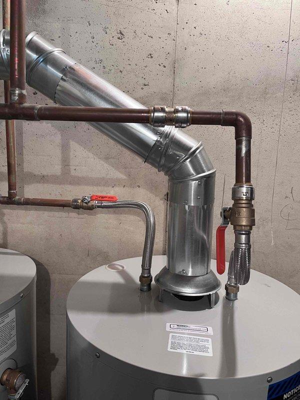 # Tanked Water Heater Installation

Completed professional installation of gas-fired tanked water heater system in basement utility area. Installation included proper venting configuration with metallic ductwork and exhaust piping, connection of copper supply lines with shut-off valves, and gas line hookup to burner assembly. All connections were secured per manufacturer specifications and local plumbing codes, with system tested and operational upon completion.