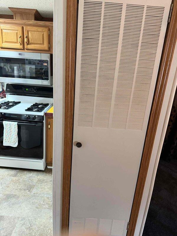 Responded to callback for furnace closet door alignment issue. Inspected louvered closet door and frame in hallway adjacent to kitchen area, verified door was not closing properly due to misalignment. Adjusted door hardware and strike plate to ensure proper latching and secure closure, restoring full functionality to furnace closet access point.