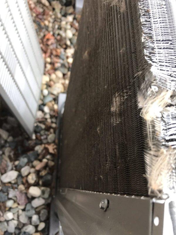 # Annual AC Maintenance Visit

Completed comprehensive annual air conditioning maintenance service as part of prepaid membership agreement. Upon arrival, performed thorough visual inspection of outdoor condenser unit positioned on gravel pad against exterior wall. Unit exhibited significant accumulation of dirt, dust, and environmental debris on condenser coils and fin assembly, indicating extended operation since last service.

Performed complete AC tune-up including the following procedures: inspected condenser unit exterior housing and verified structural integrity of mounting components and base pad. Examined electrical connections at outdoor unit and verified secure terminations. Assessed refrigerant line insulation and PVC condensate drainage system for proper installation and function.

Focused attention on heavily soiled condenser coil fins which displayed dark brown to black discoloration with substantial debris buildup between corrugated channels. Cleaned condenser coils usin