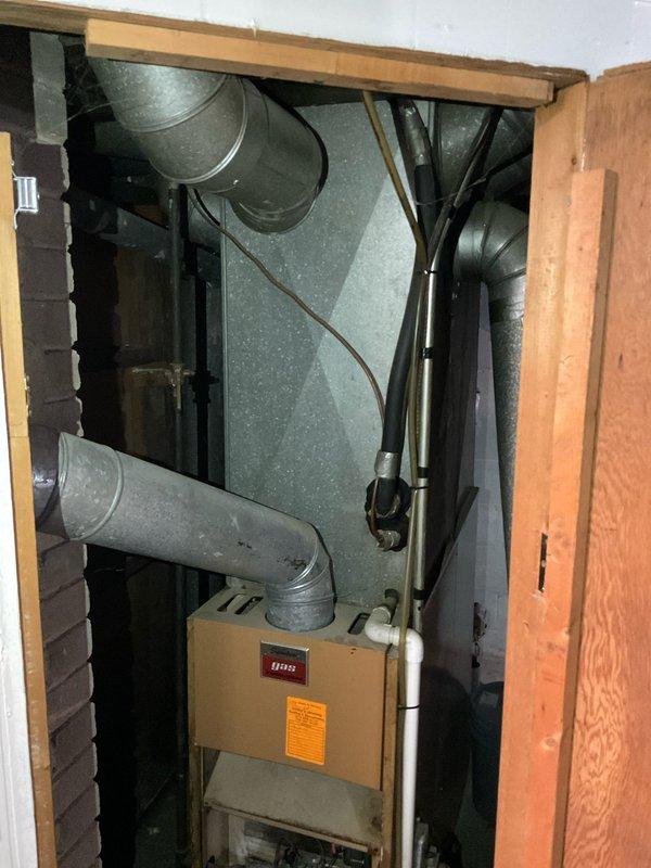 Performed comprehensive assessment of existing 25-year-old furnace and air conditioning system in single-family residence to provide replacement estimate. Documented aging HVAC equipment with minimal AC functionality, photographed furnace installation in confined utility space showing outdated ductwork configuration, and evaluated electrical panel capacity for new equipment installation requirements.