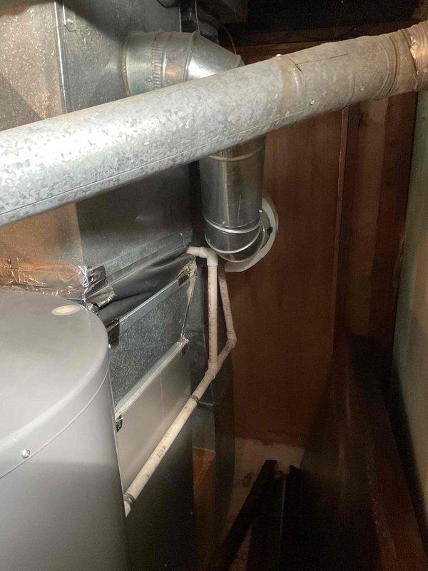 Conducted comprehensive assessment of existing 14-year-old HVAC system to provide replacement estimate. Inspected air handler unit, ductwork connections, and associated mechanical components in basement utility area. Documented current system configuration including metallic ductwork, insulated supply lines, PVC condensate drainage, and equipment placement within confined mechanical space. Photographed existing installation showing galvanized duct transitions, air handler positioning, and structural constraints for replacement planning purposes.