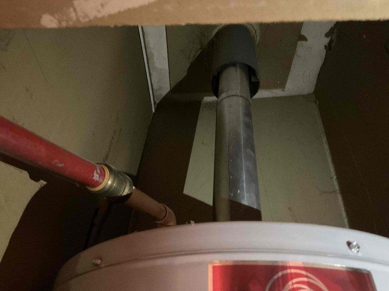Completed water heater replacement estimate at mobile home park location. Assessed existing gas water heater installation including venting system, supply line connections, and spatial constraints within utility closet. Documented current configuration showing standard atmospheric vent water heater with metal flue pipe penetrating through ceiling, red-coded hot water supply piping with brass fittings and dielectric unions, CPVC cold water supply connections, and flexible aluminum vent duct work. Evaluated clearances, access points, and existing plumbing infrastructure to provide accurate replacement specifications and labor requirements.