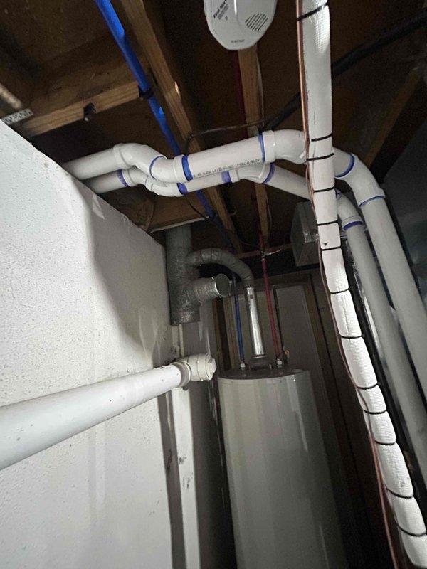Completed full HVAC system installation including a 70,000 BTU furnace, 2.5-ton air conditioning unit with rear discharge configuration, and whole-home humidifier. Performed all mechanical and electrical connections, installed condensate drainage system with PVC piping secured to floor joists, and reconnected existing ductwork to new equipment. Left programmable thermostat with property owner for future installation.