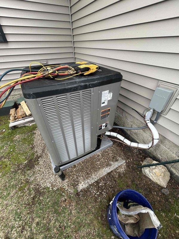 Responded to warranty call for AC unit that became unlevel following winter season. Upon arrival, connected manifold gauge set to service ports and performed refrigerant charge verification on the condensing unit. System was evaluated for levelness and operational parameters were checked to ensure proper function. Unit photographed with active gauges connected, showing refrigerant lines and electrical disconnect in place at exterior installation location.