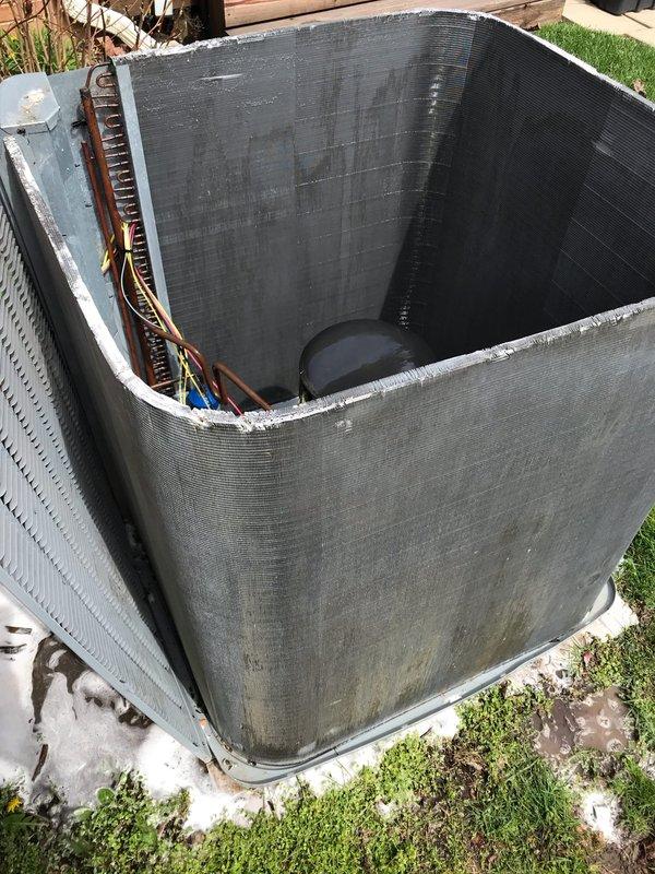 Completed annual air conditioning maintenance and tune-up on outdoor condensing unit. Removed exterior panels to access internal components, inspected condenser coils which showed normal dirt accumulation and weathering from outdoor exposure. Verified refrigerant lines, electrical connections including yellow and blue wiring, and compressor assembly. Noted deteriorated foam insulation along top edge of unit and debris around base pad. System operational and ready for cooling season.