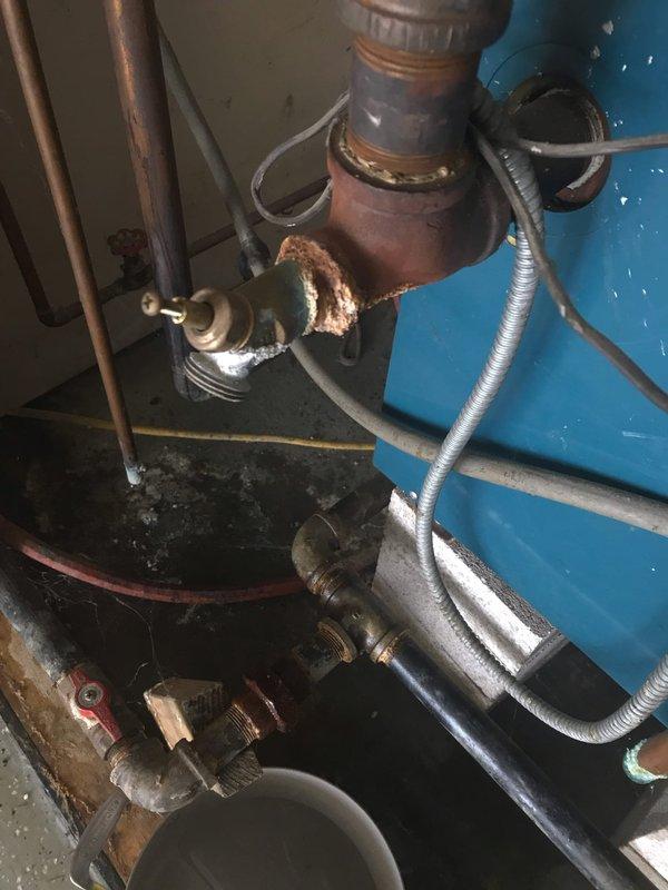 Responded to service call for reported boiler leak with significant dripping from piping. Upon inspection, identified severe corrosion on copper pipe fitting and joint connections near boiler assembly. Corrosion had compromised the integrity of the connection, causing active water leak. Documented existing conditions with photographs showing corroded copper components, pressure gauge readings, and overall boiler system configuration including specification plate indicating unit manufactured in June 2000. Performed annual maintenance inspection in conjunction with leak assessment. Examined all visible piping connections, flexible gas lines, valve assemblies, and corrugated stainless steel tubing throughout the system. Verified pressure readings on mounted gauge and inspected control wiring connections. Provided customer with documentation of corroded components requiring replacement and recommended immediate repair to prevent further water damage and potential system failure.