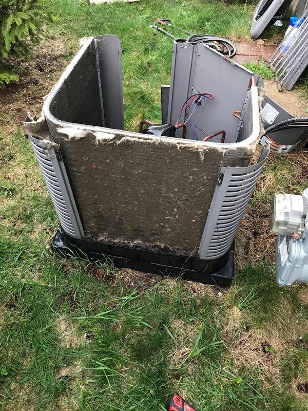 Completed prepaid AC tune-up maintenance visit on residential air conditioning system. Performed comprehensive inspection of outdoor condenser unit, including removal of outer casing to access internal components for thorough cleaning and evaluation. Observed significant dirt and debris accumulation on exterior housing and internal surfaces, with visible weathering and white residue deterioration around top rim edges. Inspected electrical control boxes, wiring connections, and refrigerant line routing to ensure proper operation. Examined condenser coils with aluminum fins on multiple sides for airflow efficiency. Verified unit mounting on platform pad and assessed overall system condition. Documented equipment condition through photographs showing internal components, copper refrigerant lines, and external housing. System operational upon completion of maintenance procedures.