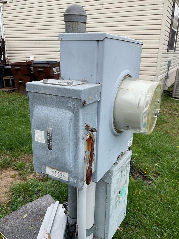 Completed site assessment for new air conditioning system installation at residential mobile home with no existing AC infrastructure. Evaluated electrical service panel and meter assembly in backyard to confirm adequate power supply capacity for new system installation. Inspected interior utility closet housing existing furnace/air handler unit to determine optimal placement and integration approach for new cooling equipment. Documented existing beige cabinet-style air handler with dual louver configuration and verified available space for refrigerant line routing and condensate drain installation. Assessed electrical service connections, outdoor condenser pad location requirements, and necessary modifications to accommodate complete split-system air conditioning installation.