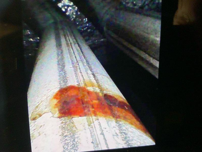 Responded to no-cool complaint on 9-year-old central air conditioning system. Customer reported inadequate cooling performance with temperature dropping only 4 degrees over 5 hours and outdoor unit discharging cool air instead of normal hot air, indicating refrigerant circuit issue. Upon inspection, identified significant rust staining and corrosion inside evaporator coil assembly, confirmed through borescope camera inspection of ductwork and coil housing. Rust bleeding pattern suggests advanced deterioration of evaporator coil with likely refrigerant leak. Documented internal coil damage with inspection camera showing extent of corrosion on coil surfaces. Outdoor unit discharging cool air confirms loss of refrigerant charge and system operating in failed state with compressor running but no heat transfer occurring. Recommended evaporator coil replacement due to corrosion damage and system recharge with proper refrigerant after leak repair. Customer provided photographic evidence of in