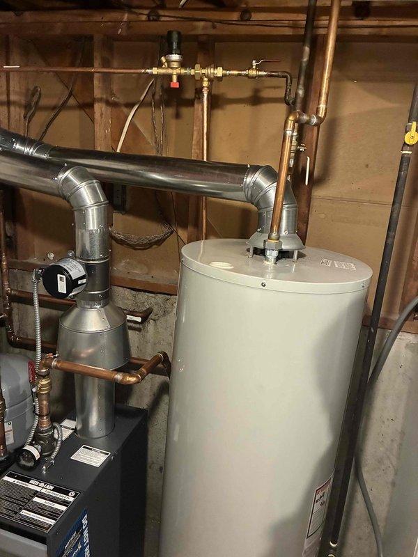 Completed full boiler installation in residential basement including mechanical, electrical, and venting connections. Installed new boiler unit with proper ductwork configuration featuring galvanized metal components and elbow joints, connected expansion tank with copper piping and brass fittings, and integrated system with existing water heater. All reconnections completed, system tested and operational.