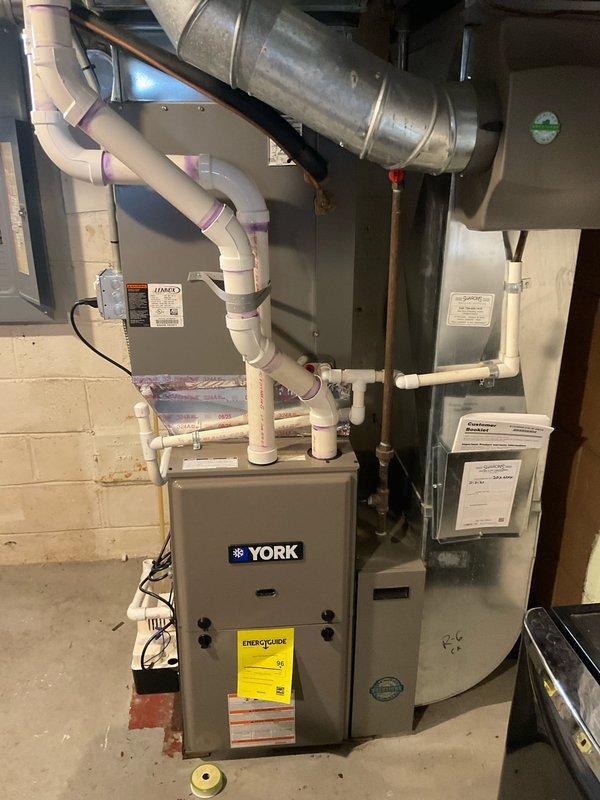 Conducted on-site evaluation for HVAC system replacement at residential property. Assessed existing York furnace and air handler unit located in basement mechanical room, documenting current equipment configuration including condensate drainage system, PVC venting network, and ductwork connections. Evaluated exterior condensing unit positioned in overgrown side yard area adjacent to building, noting accessibility challenges due to vegetation encroachment. Prepared comprehensive replacement estimate quotes 03625-07 and 03625-03 with photographic documentation of existing system components and installation environment.