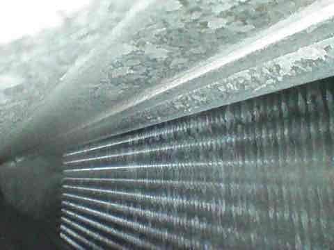 Completed preventive maintenance tune-up on HVAC system. Inspected evaporator coil assembly and found moderate dust accumulation between fins and oxidation on exterior housing panel. Documented existing wear patterns on equipment including paint deterioration and surface corrosion on metal casing, with unit showing signs of age-related exposure. All critical components checked and system operational at time of service completion.