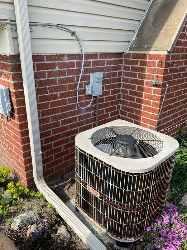Performed estimate for HVAC system replacement on R22 unit found to be low on refrigerant charge. Evaluated existing indoor furnace/air handler unit in basement utility area and outdoor condensing unit positioned at exterior brick wall. Documented current system configuration including condensate drainage, electrical disconnect, and overall equipment condition to provide replacement options for aging R22 system.