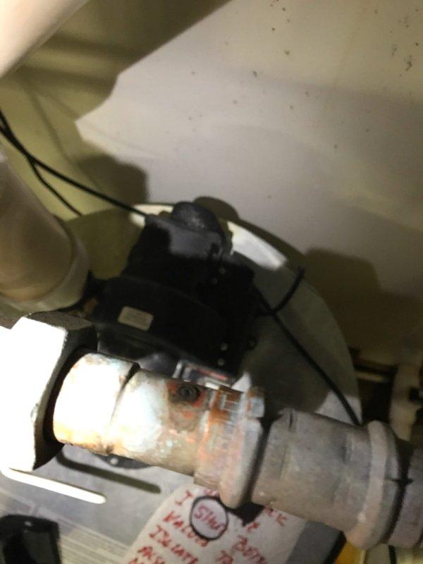 Responded to water heater leak complaint and performed thorough inspection of tanked water heater system and associated plumbing connections. Upon examination, identified source of leak at copper pipe connection point near water heater assembly. Inspected PVC and copper piping configuration, including valve assembly and pump components in utility space. Documented condition of water heater showing surface discoloration and staining consistent with moisture exposure and age-related wear. Photographed plumbing assembly including white PVC elbows, copper piping with chrome valve featuring star-shaped handle, and connection points where leak was occurring. Assessed overall system integrity and identified necessary repairs to address pinhole leak in copper pipe section to prevent further water damage and restore proper system function.