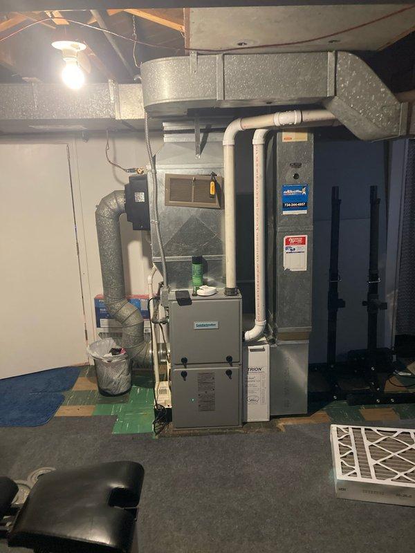 Completed prepaid annual air conditioning maintenance on residential HVAC system located in basement mechanical room. Performed comprehensive AC tune-up including inspection of furnace, ductwork, humidifier unit, and associated components. System components inspected included galvanized metal ductwork with visible mineral deposits on humidifier supply plenum, copper refrigerant lines, white PVC condensate drainage, and air filtration system. All mechanical equipment evaluated for proper operation and seasonal readiness, with photographic documentation captured of equipment condition and installation.