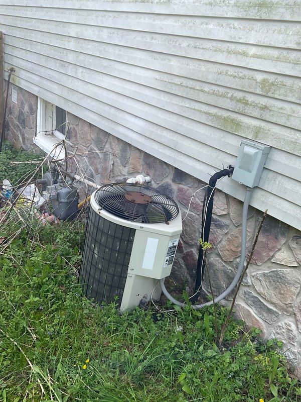 Completed comprehensive HVAC system replacement estimate for 10-12 ton capacity installation. Evaluated existing ductwork infrastructure in basement utility area, including galvanized sheet metal trunk lines and branch ducts, and assessed exterior equipment placement area with two existing condenser units positioned against foundation. Documented current system configuration and site conditions to prepare detailed replacement proposal for veteran homeowner requiring financing options.