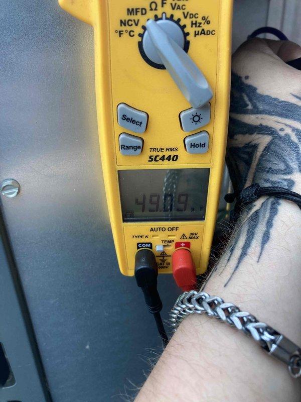 Completed preventive maintenance tune-up on HVAC system. Inspected electrical disconnect switch mounted on exterior wall, noting accumulation of cobwebs and dirt consistent with outdoor exposure. Verified disconnect switch operation and confirmed unit specifications on Model No. 83316 label. Performed voltage testing using digital multimeter, recording 49.99 volts at time of measurement to assess electrical performance and system functionality.