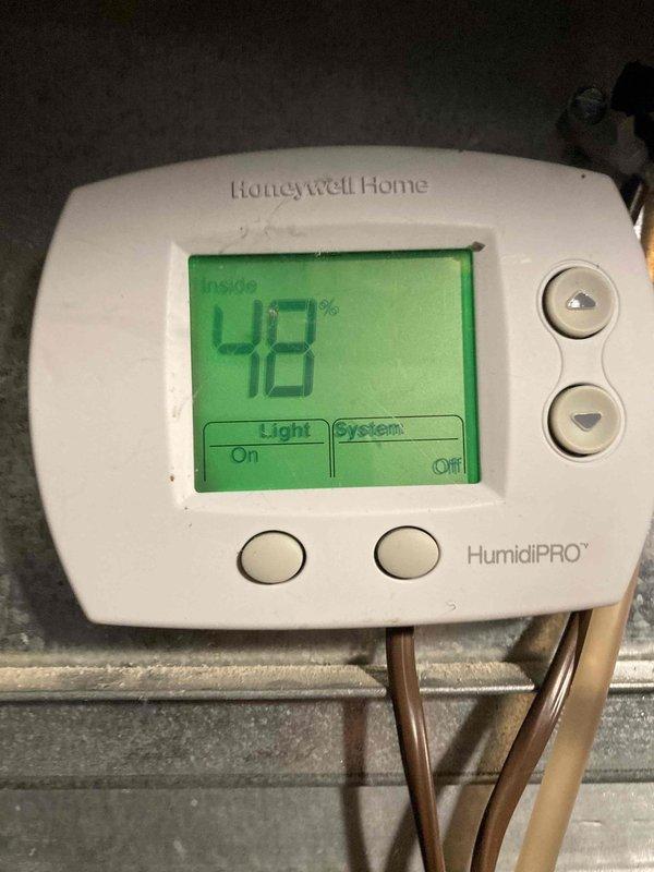 Completed routine HVAC maintenance agreement visit including air conditioning and system inspection. Verified Honeywell Home HumidiPRO humidistat operation showing 48% indoor humidity with system in off mode and light function active. Performed electrical diagnostics using digital multimeter, recording 0.66 AC voltage readings to confirm proper system operation and control circuit functionality.