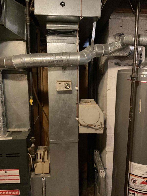Performed comprehensive system evaluation of aging HVAC equipment including a 16-year-old Goodman furnace and 14-year-old air conditioning unit located in basement mechanical room. Assessed existing ductwork configuration, gas line connections, and electrical components. Documented current system condition through photographic documentation showing furnace cabinet, air handler, metal ductwork with moisture presence, and associated utility infrastructure. Provided complete system replacement estimate as alternative to repair options after determining equipment age and condition warranted full replacement consideration.
