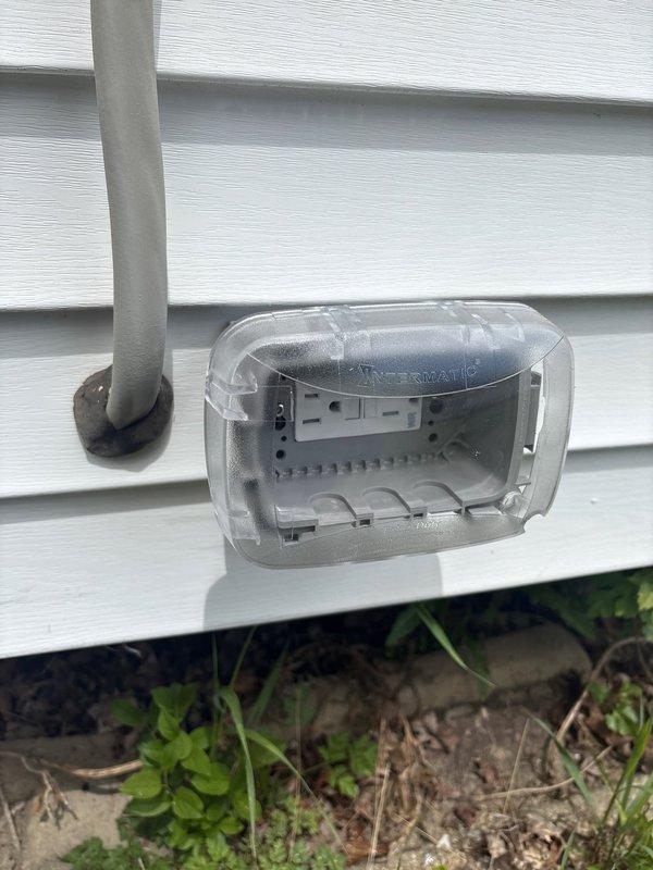 Installed ground fault circuit interrupter (GFI) outlet with weatherproof cover on exterior wall. Ran gray PVC conduit vertically along white vinyl siding to protect wiring from environmental exposure. Mounted outdoor-rated electrical box with clear hinged weatherproof cover to allow access while maintaining protection from moisture and weather elements. Verified proper grounding and tested GFI functionality to ensure compliance with electrical safety standards for outdoor receptacles.