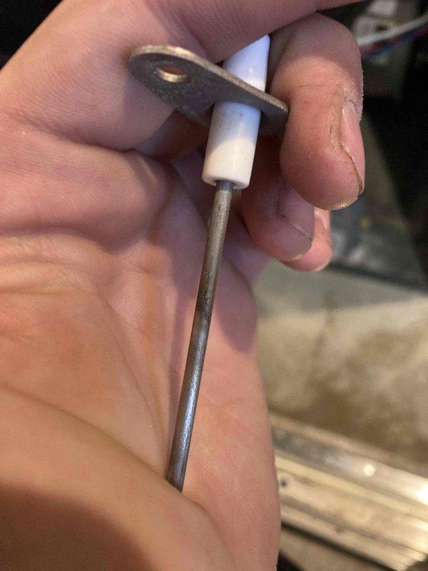 Completed comprehensive AC/furnace tune-up inspection and maintenance. Removed and inspected flame sensor rod, which showed signs of oxidation buildup on the ceramic insulator and sensor probe. Extracted dual-run capacitor from outdoor condensing unit for testing, revealing age-related wear and discoloration on the housing with multiple wire connections intact at terminals.