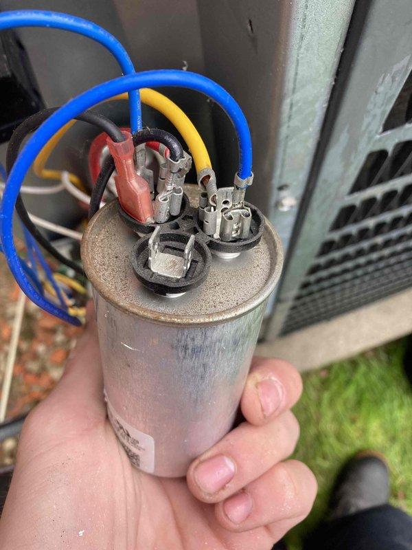 Completed comprehensive AC/furnace tune-up inspection and maintenance. Removed and inspected flame sensor rod, which showed signs of oxidation buildup on the ceramic insulator and sensor probe. Extracted dual-run capacitor from outdoor condensing unit for testing, revealing age-related wear and discoloration on the housing with multiple wire connections intact at terminals.