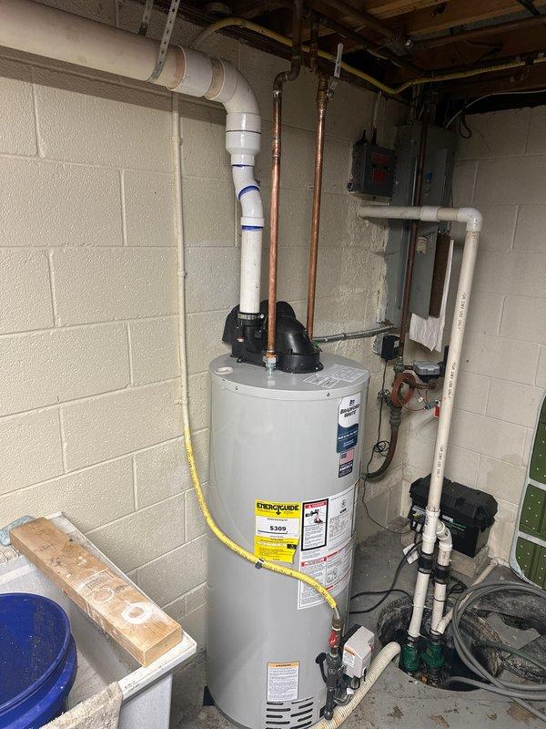 Completed installation of residential tanked water heater in basement utility room. Connected hot and cold water supply lines using copper piping and flexible braided hoses with appropriate shut-off valves. Installed yellow flexible gas line connection to unit and verified proper gas flow. Routed corrugated metal exhaust vent duct for proper ventilation. Connected electrical power supply and verified operational functionality. Installed temperature and pressure relief valve with discharge piping per code requirements. Tested all plumbing connections for leaks and confirmed water heater is heating properly and operating safely.