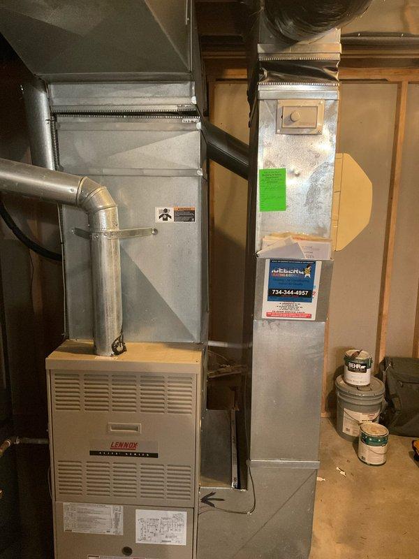 # HVAC System Estimate - Replacement Assessment

Conducted comprehensive assessment of existing Lennox furnace system located in basement utility area for replacement estimate. Evaluated current equipment configuration including furnace unit, metal ductwork system, and air handler components. Documented existing installation showing furnace with ventilation louvers, manufacturer specification labels, and connected galvanized steel ductwork extending vertically with horizontal connections. Noted flexible black ductwork at ceiling level and metallic elbow duct connections. Photographed complete system layout including equipment positioning against wall framing, PVC drainage piping, and floor drain location for replacement planning purposes. Provided detailed system estimate for 8-10 SEER replacement equipment options.